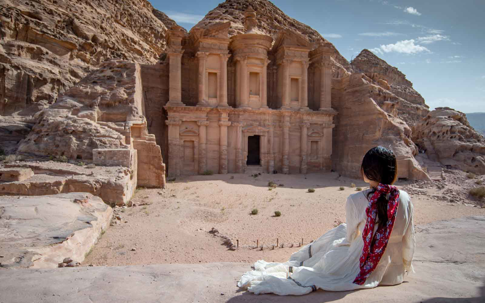 woman sitting before rock cave carved entrance to petra