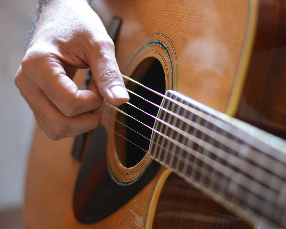 close up of fingers struming acoustic guitar