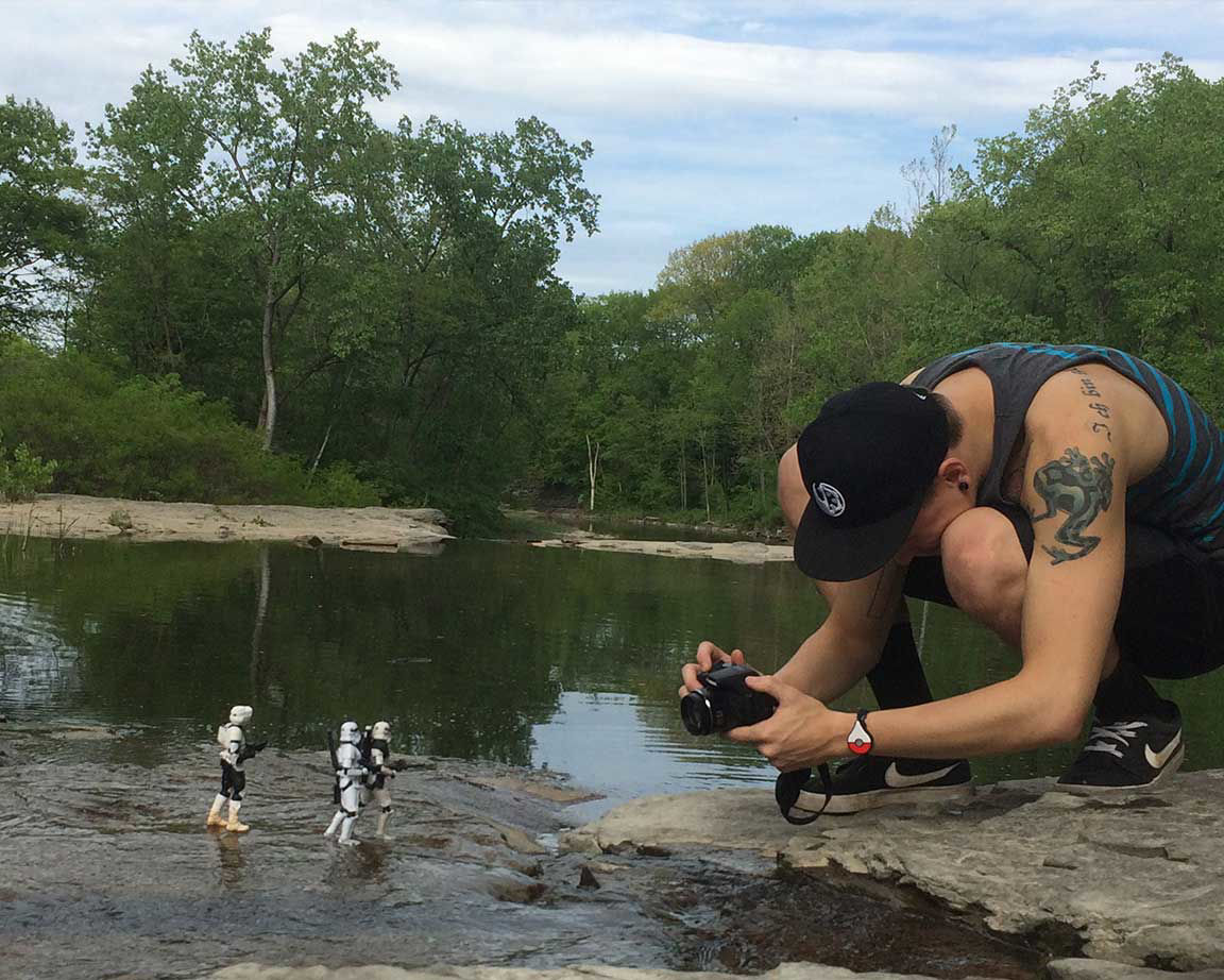 photographer kneeling on rocks photographing star wars toys